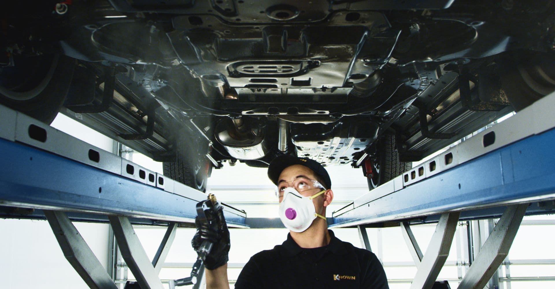 Technician applying undercoating, showcasing the benefits of booking your rustproofing at Gatineau.